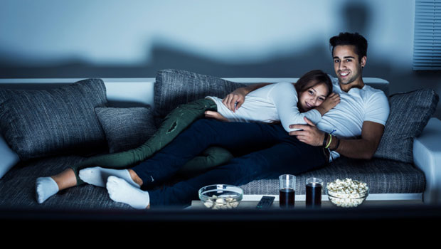 Couple watching a movie on a sofa.